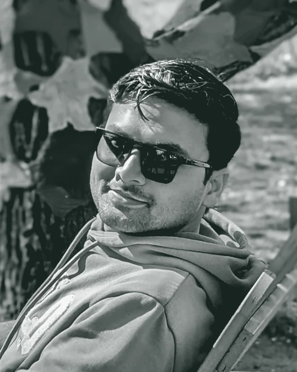Hussain Raza, smiling, seated outdoors